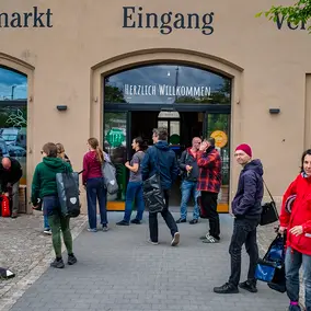 Teilnehmer:innen der Tour der Utopien stehen vor dem Biomarkt Friedensstraße.