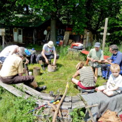 Sieben Menschen sitzen im Garten der Johannishöhe in einem Bankkreis