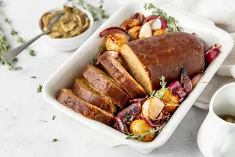 Veganer Braten mit Ofengemuese in einer weißen Form