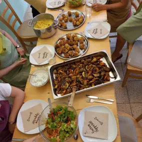 Teilnehmer beim Kochworkshop Regionale Küche essen gemeinsam an einem Tisch, darauf zubereitete Gerichte