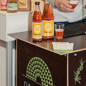 Kombucha wird an einem Stand von Elb-Ferment abgefüllt. Produkte von Elb-Ferment werden präsentiert.