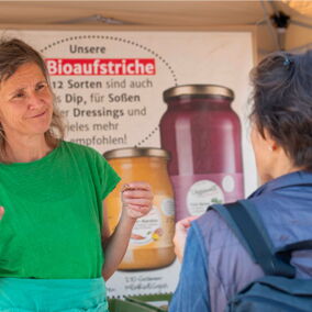 Mitarbeiterin von Vegannett spricht mit Besucherin an ihrem Stand