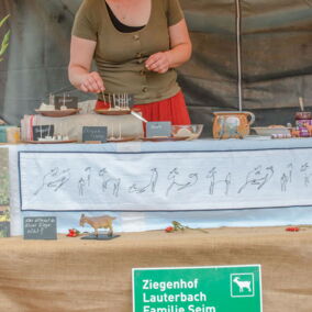 Eine Frau steht am Stand des Bioland-Betriebes Ziegenhof Lauterbach und präsentiert Käsesorten
