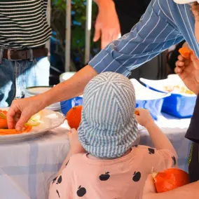 Zwei Kinder stehen mit einem Erwachsenen an einem Stand und probieren Paprika