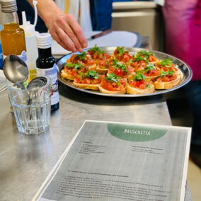 Eine Teilnehmerin beim Kochworkshop belegt Bruschetta