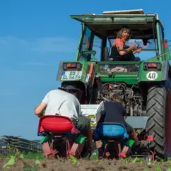 Ines Franz und zwei Mitarbeiter auf einem Traktor bei der Feldarbeit