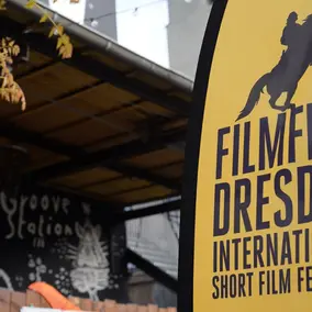 Bowflag des Dresden International Short Film Festival 2026, dahinter die Groove Station Dresden.