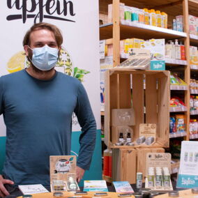 Ein Mann steht an einem Tisch, darauf eine Auswahl von Biokosmetik von Lipfein