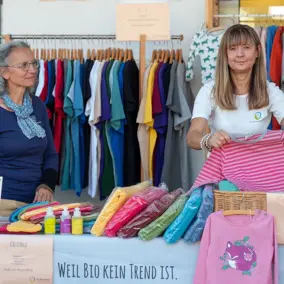 Zwei Frauen betreuen den Stand des Naturwarenladens und legen Kleidung zusammen