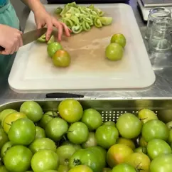 Eine Person schneidet grüne Tomaten