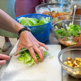 Teilnehmer beim Kochworkshop Regionale Küche schneidet Salat