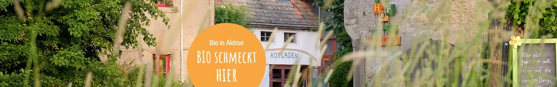 Hofansicht Hof Mahlitzsch. Text auf orangem Kreis: Bio in Aktion. Bio schmeckt hier.