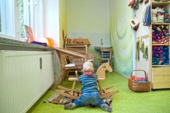 Ein Kleinkind spielt in der Kinderecke, im Hintergrund ein Wickeltisch mit Waschbecken