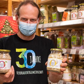 Mitarbeiter der Verbrauchergemeinschaft Dresden zeigt zwei Gläser mit Produkten von Unverpackt für Alle