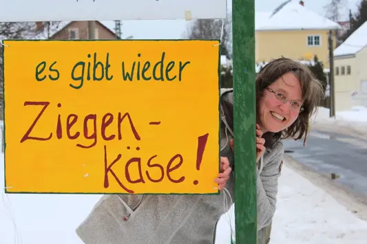 Doreen Seim vom Ziegenhof Lauterbach mit einem Schild mit Text: "Es gibt wieder Ziegenkäse"