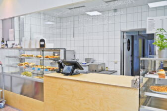 Kasse und Theke mit herzhaften und süßen Speisen in der Auslage im Biobistro