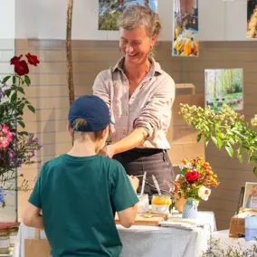Regionale Lieferantin der VG spricht mit einem Jungen an einem Stand