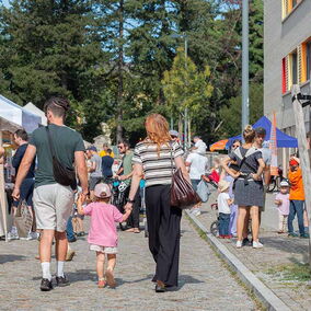 Eine Familie mit Kind schlendert über ein Festgelände mit vielen Menschen
