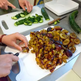 Teilnehmer beim Kochworkshop Regionale Küche schneiden Gurken und Zwetschgen