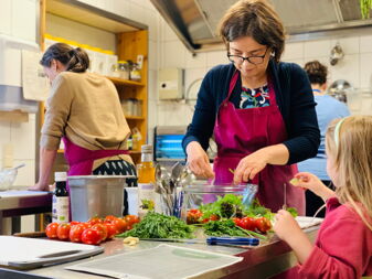 Frau mit Kind kocht beim Regional-Kochworkshop