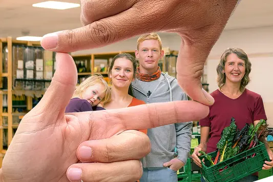 Mitglieder der Verbrauchergemeinschaft, im Vordergrund formen zwei Hände einen Rahmen um ihre Gesichter