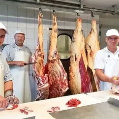 Drei Mitarbeiter der Bio-Fleischerei Mörl zerteilen Fleisch