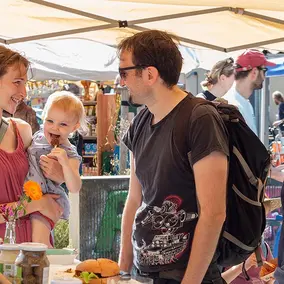 Familie mit Kind steht an einem Stand auf dem Regionalfest