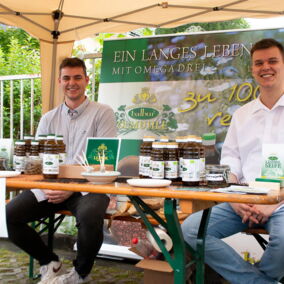 Verschiedene Öle der Bio-Ölmühle Balbur auf einem Tisch präsentiert, zwei sitzende Mitarbeiter