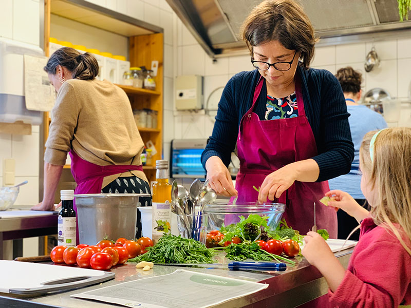 Frau mit Kind kocht beim Regional-Kochworkshop