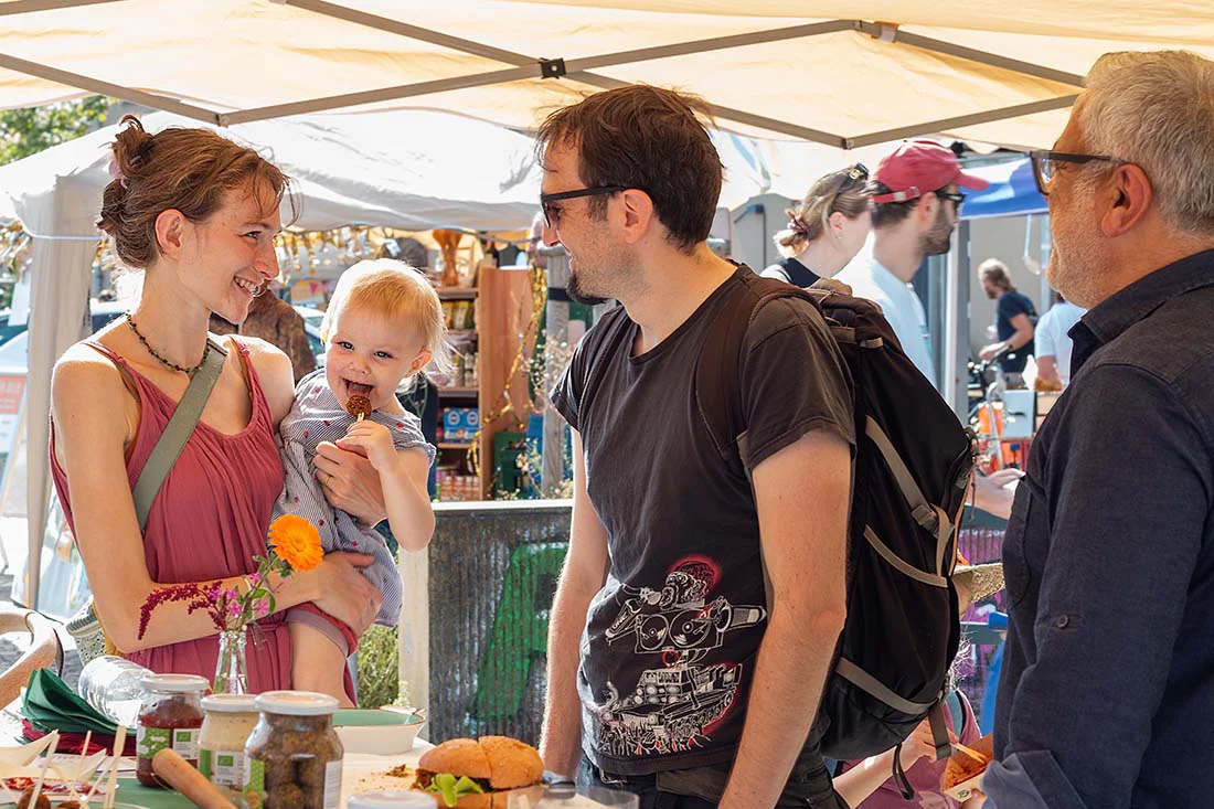 Familie mit Kind steht an einem Stand auf dem Regionalfest