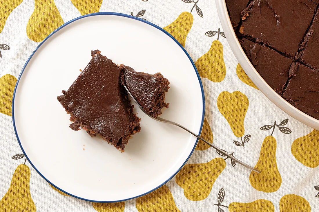 Haselnuss-Brownie auf einem Teller neben einer Brownieform