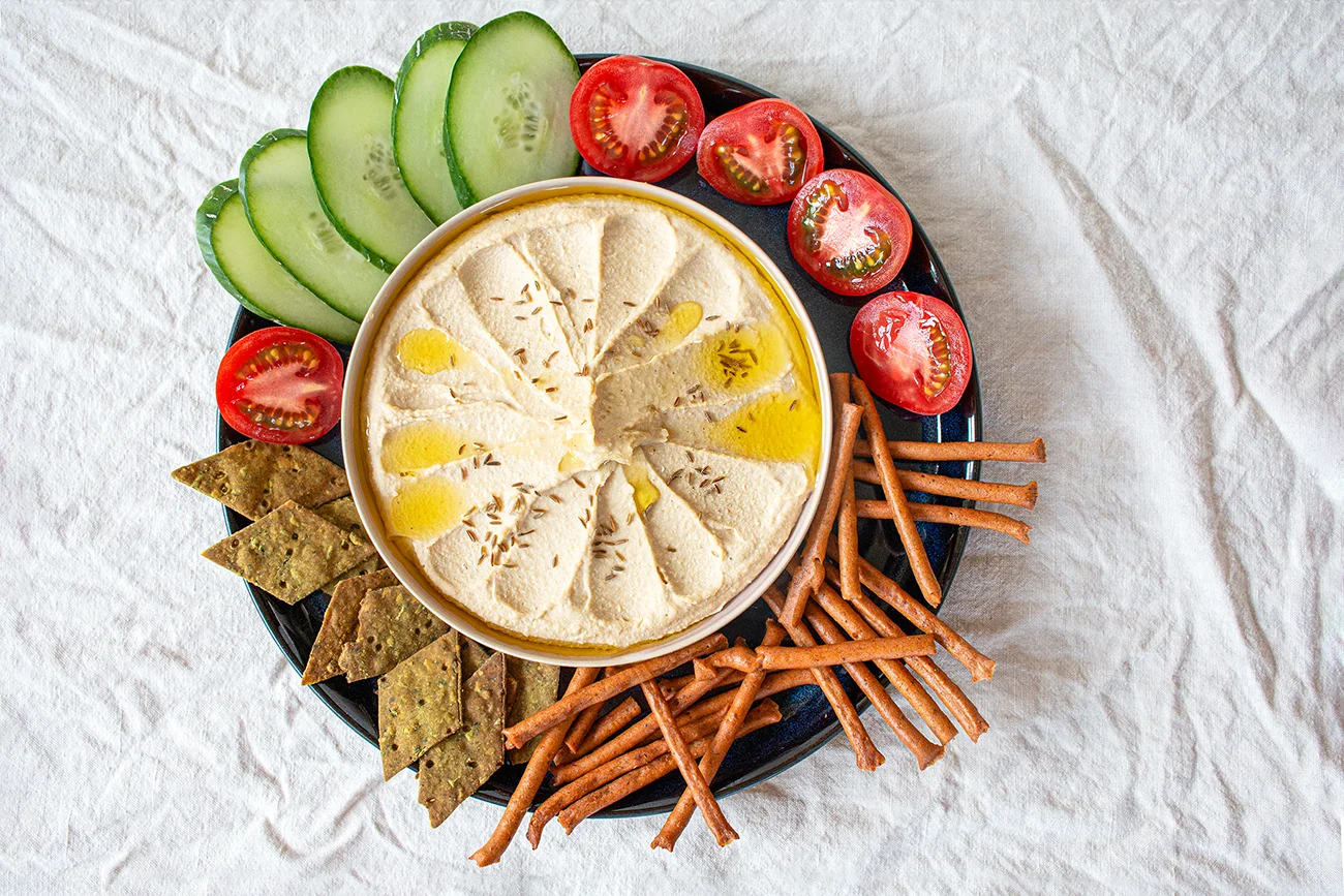 Hummus aus Süßlupinensamen in einer Schale, mit Tomaten, Gurken und Knabbergebäck