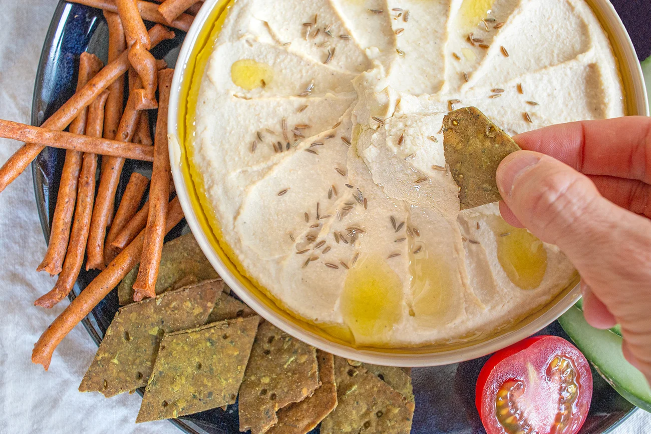 Hand dipt Hummus aus Süßlupinensamen aus einer Schale
