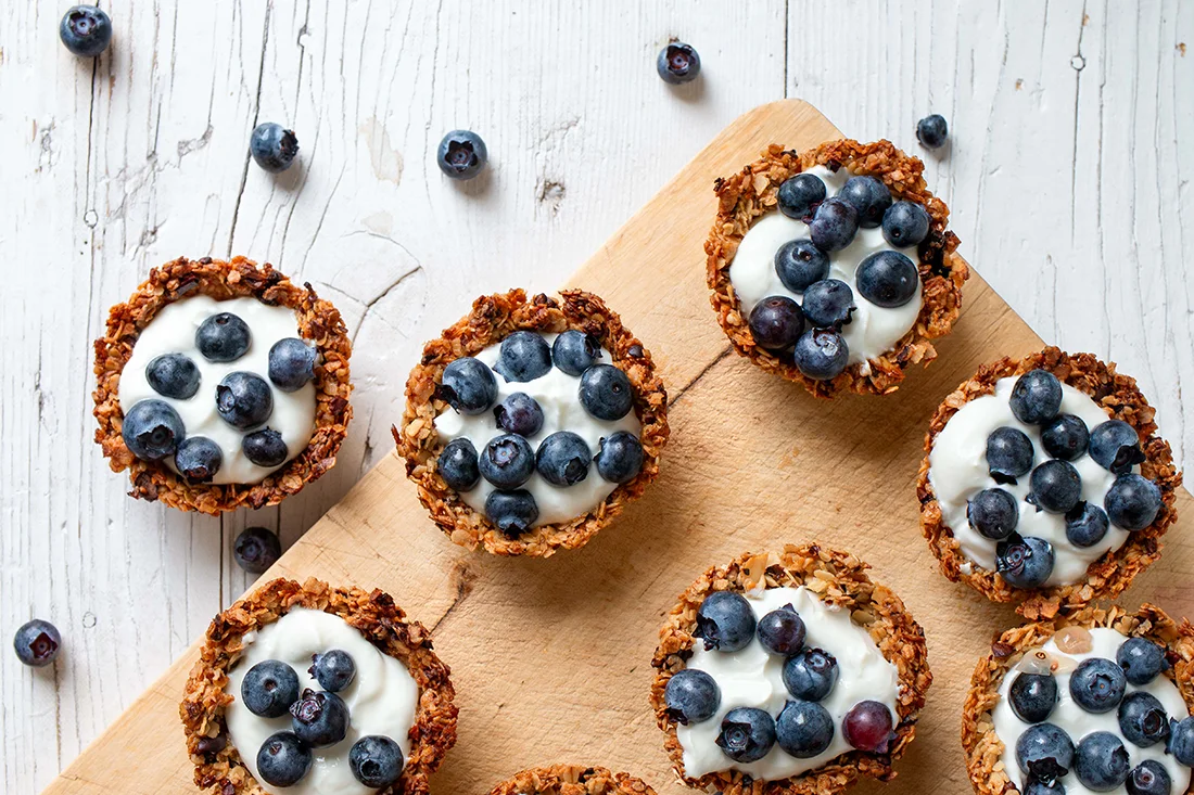 Müsli Törtchen mit Vanillequark und Heidelbeeren auf einem Brett