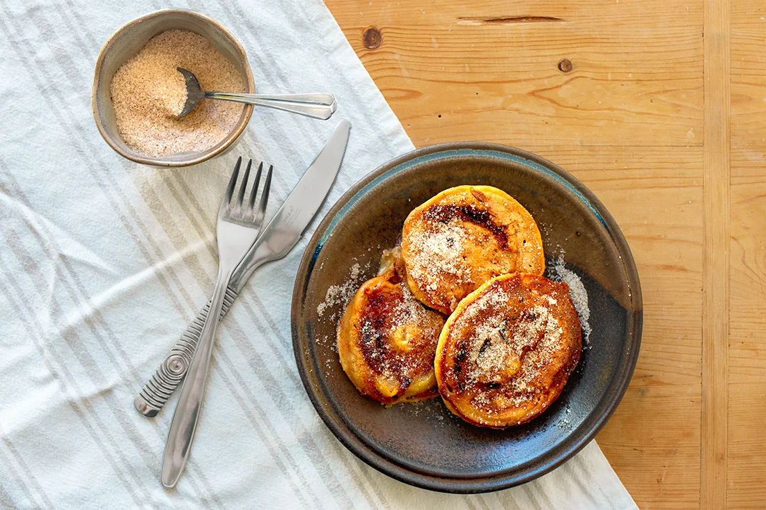 Apfelküchlein auf einem Teller mit Zimt und Zucker