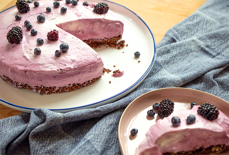 angeschnittener Cheesecake mit Beeren und Knusperboden, ein einzelnes Stück Kuchen auf einem Teller