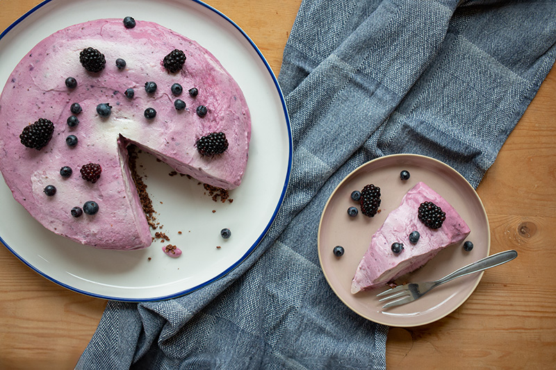 angeschnittener Cheesecake mit Beeren und Knusperboden, ein einzelnes Stück Kuchen auf einem Teller