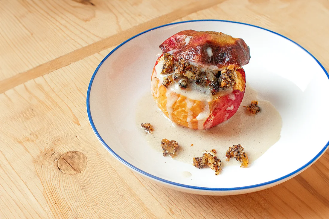 Bratapfel mit Mohn-Aprikosen Füllung und Vanillesauce auf einem Teller angerichtet