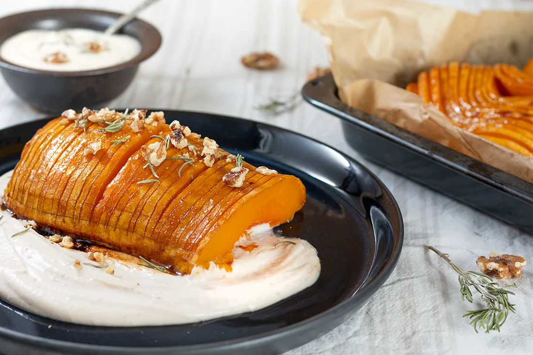 Hasselback-Kürbis mit Feta-Bohnencreme auf einem Teller