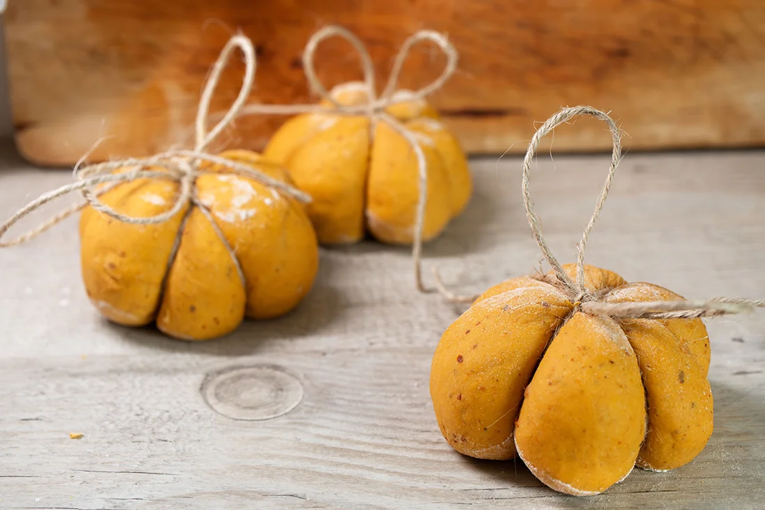 drei ungebackene Kürbis-Brötchen mit Küchengarn umwickelt