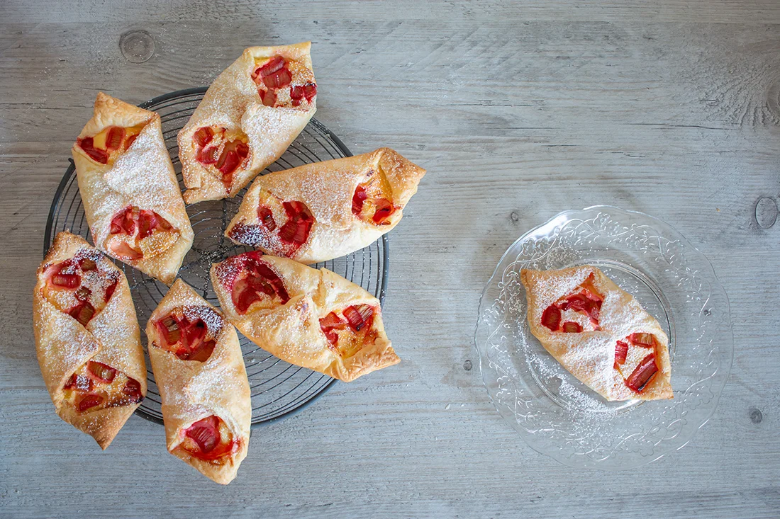 Rhabarber Schiffchen mit Quark und Blätterteig auf einem Rost und einem Teller