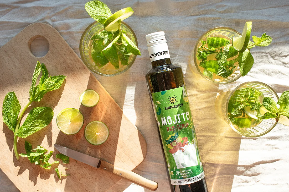 Virgin Mojito mit Mojito Bio Sirup von Sonnentor, Minze und Limette auf einem Brett