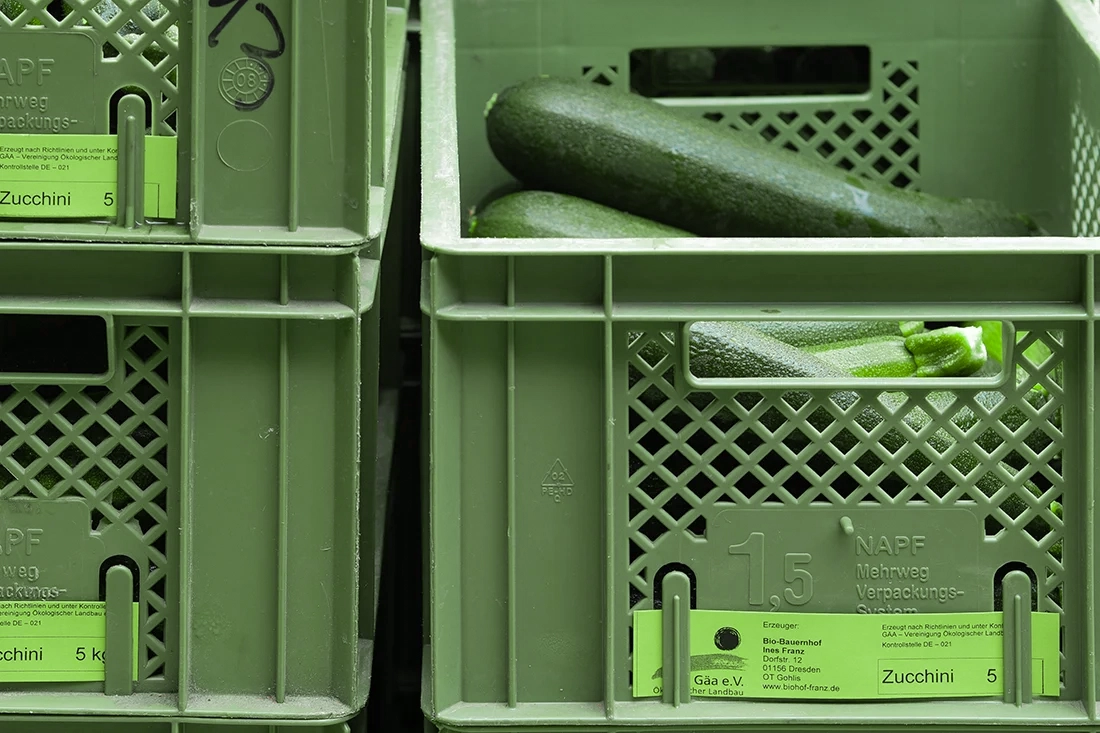 frisch geerntete Bio-Zucchini in Mehrweg-Kisten verpackt und mit Ursprungs-Schildern versehen
