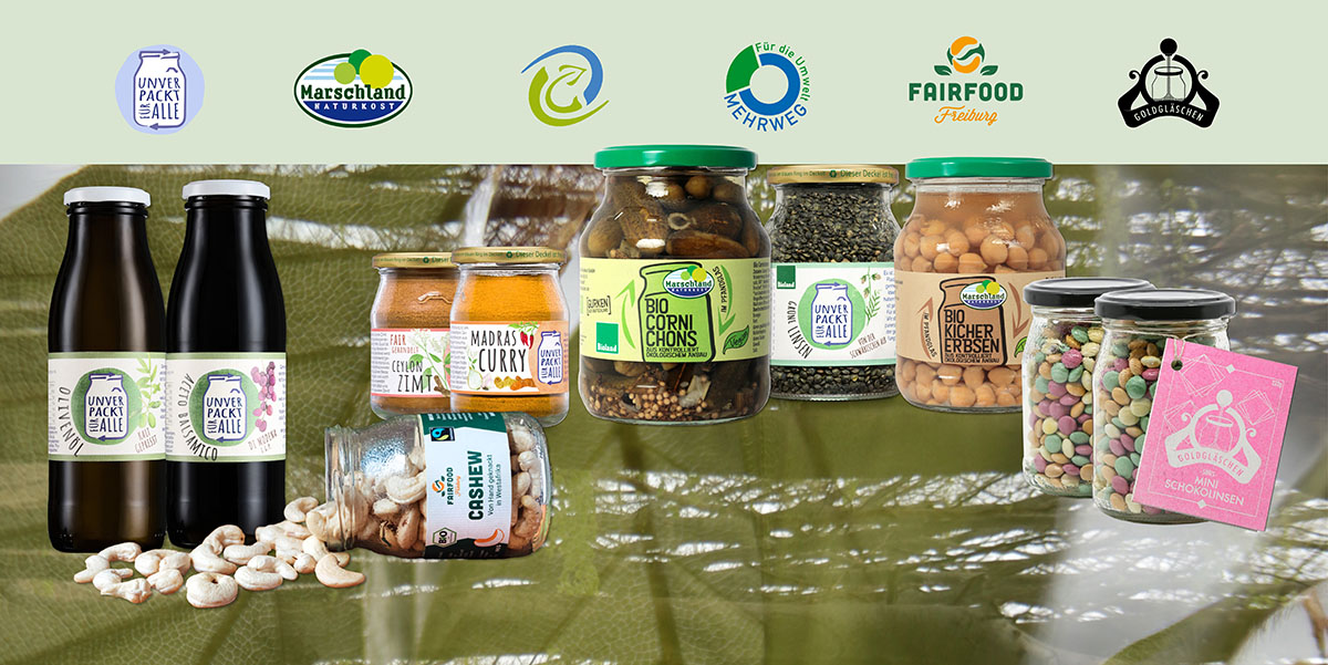 Produkte in Mehrweg-Verpackungen vor grünem Hintergrund. Gezeigt werden die Logos von Unverpackt für Alle, Marschland, VG Dresden, das Mehrweg-Logo, Fairfood Freiburg und Goldgläschen