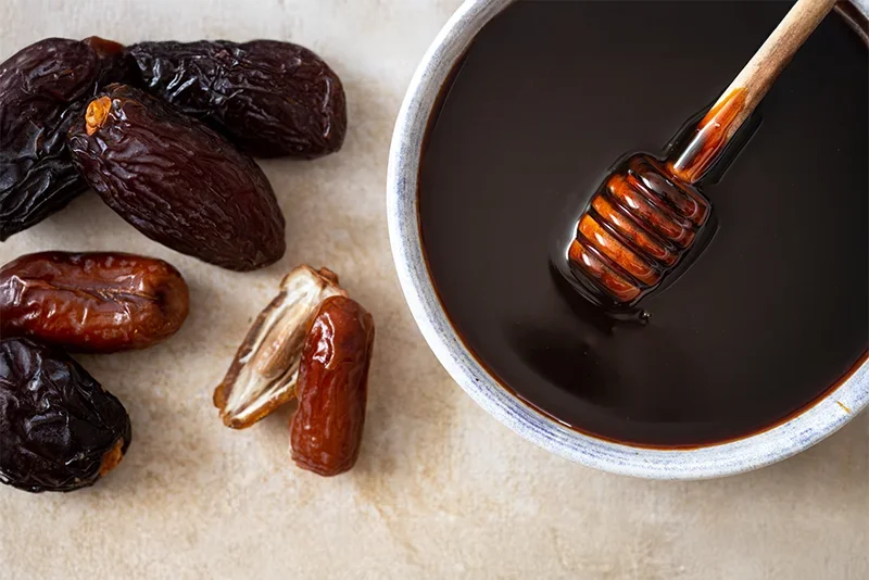 Datteln neben einer Schüssel mit Dattelsirup