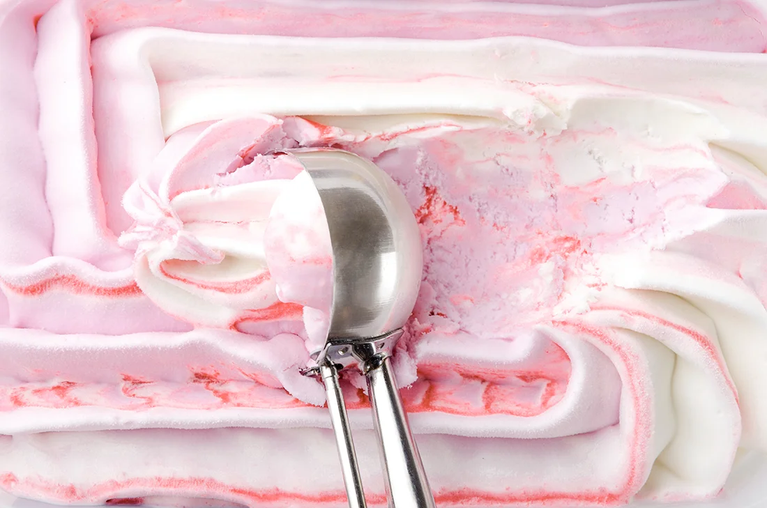 Beereneis in Nahaufnahme, darin ein Eisportionierer. Bild: AdobeStock_ uaPieceofCake