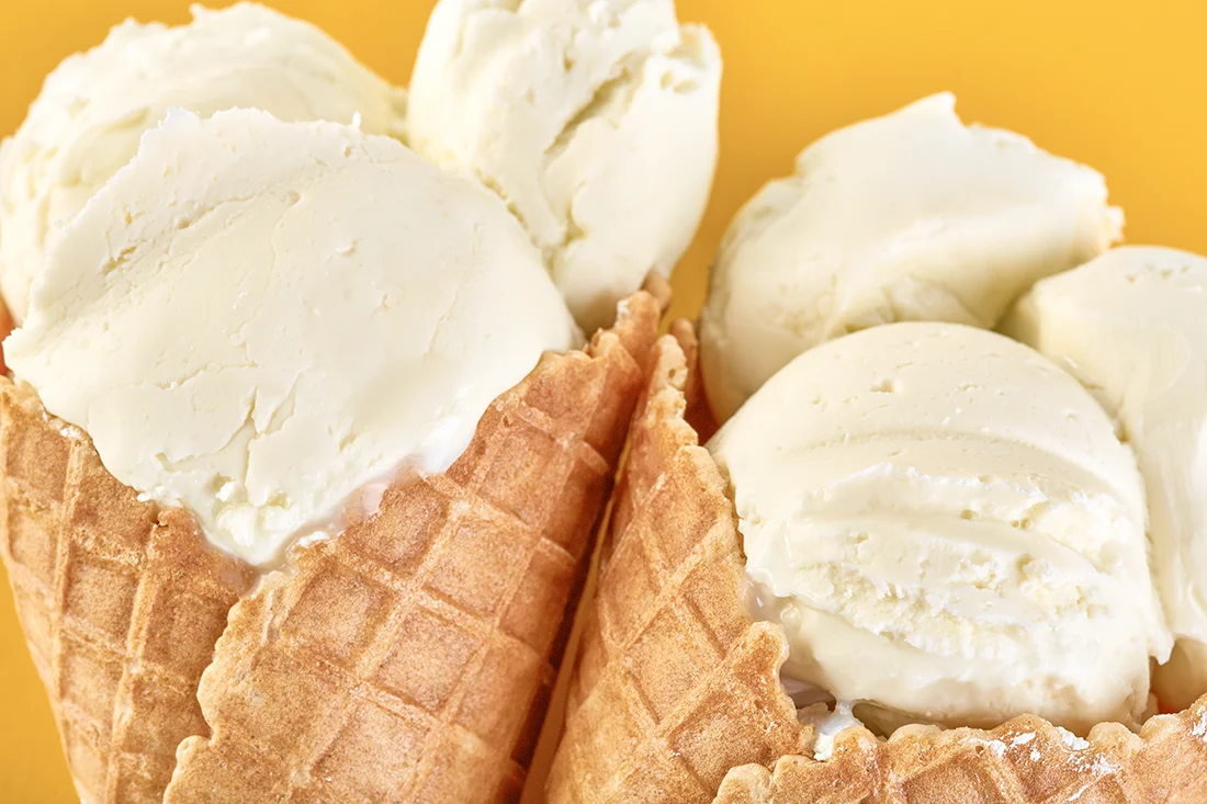 Vanilleeis in Waffeln vor orangem Hintergrund. Bild: AdobeStock/stas_malyarevsky