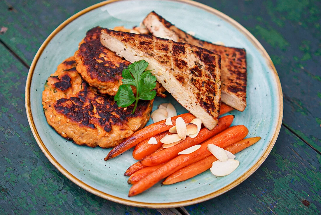 Tofu, Karotten und Patties auf einem Teller angerichtet