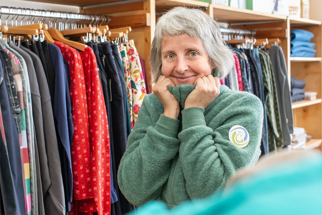 Eine Frau im Naturwarenladen kuschelt sich in einen Wollpulli