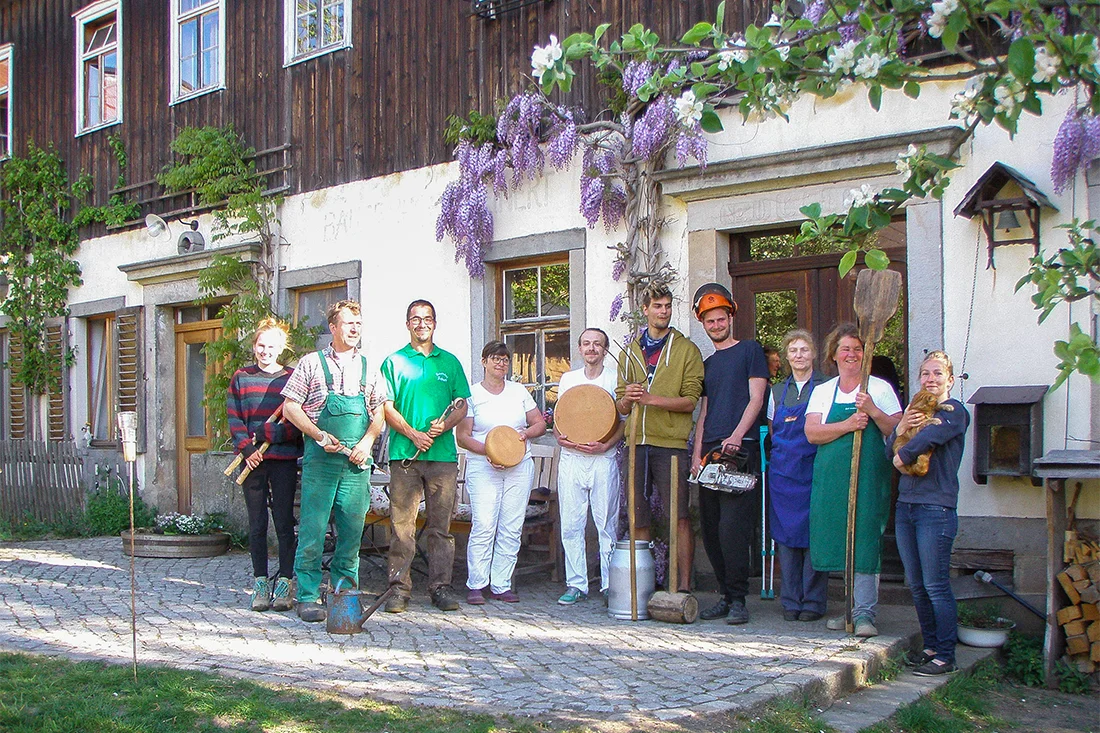 Das Team vom Bauernhof Steinert steht vor dem Hofgebäude und präsentiert Käselaibe